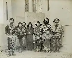 Photo d'un groupe de sept personnes alignées et portant des costumes traditionnels aïnous.