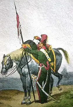 Un soldat de dos, la tête tourné vers la gauche, se tenant auprès de son cheval, avec une lance dans sa main gauche et la bride de sa monture dans sa main droite.