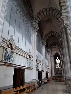 Photographie couleur d'un bas-côté d'église assez sombre.
