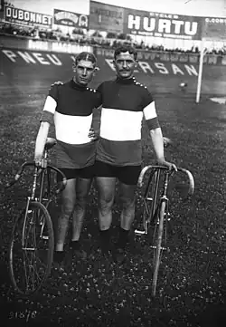 Photographie noir et blanc de deux cyclistes à l'arrêt avec leurs machines.