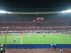 Photographie d'un stade de football avec plusieurs joueurs dessus.