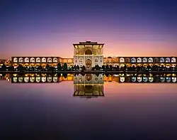 Grâce à son reflet dans un plan d'eau, vue double du palais. Les fenêtres sont éclairées, car la nuit approche.