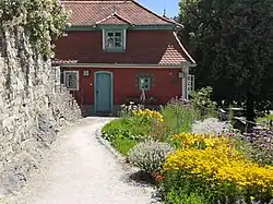 Photo en couleur d'une maison rouge avec jardin fleuri en terrasse