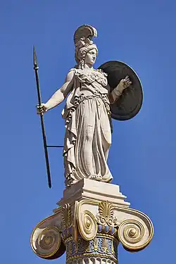 Statue d'une femme en armure. Elle porte un casque, un bouclier et une lance.