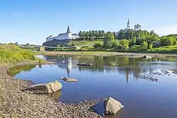 Deux collines sur lesquels reposent à gauche une église fortifiée et à droite un château. En arrière-plan se trouve une montagne enneigée.