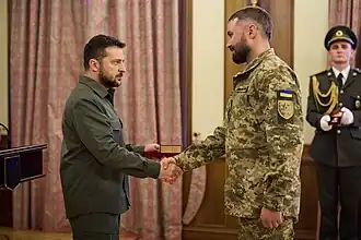 À gauche, le président Zelensky lors d'une remise de médaille,