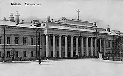 Photographie en noir et blanc d'un imposant bâtiment avec une façade à colonnades sous la neige.