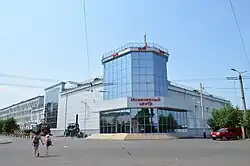 Grand bâtiment moderne de plusieurs étages, composé de fenêtres bleu ciel, sur fond de ciel entièrement dégagé.