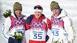 Trois skieurs posant pour les photgraphes, celui du centre tenant par les bras les deux autres.