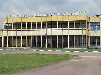 La façade délabrée d'un aéroport, portant les lettres AEROPORT INTERNATIONAL DE KISANGANI.