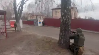 Photo couleur de trois soldats en tenue de combat dans une rue.
