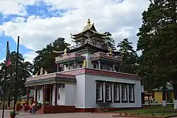 Photographie de côté d'un édifice religieux bouddhiste de trois étages, en blanc et rouge.