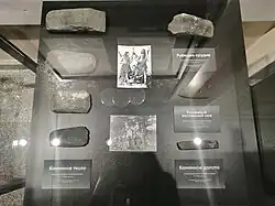 Pierres exposées dans un musée avec des indications russes, montrant au travers de 7 pierres les différents stades entre une pierre brute et une pierre polie.