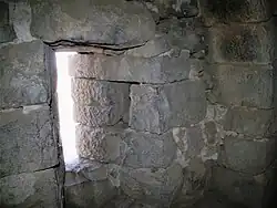 intérieur aux murs en blocs de pierre gris-bleu, ouverture en fente
