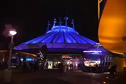 Bâtiment blanc conique éclairé par une lumière bleue.