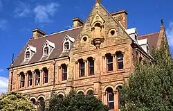 photographie en couleurs, en légère contre plongée, d'une bâtisse en pierre de style religieux victorien