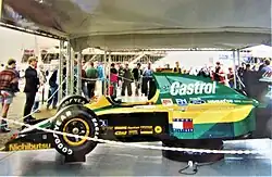 Vue du côté gauche d'une monoplace verte et jaune, dans un garage