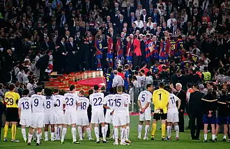 des joueurs de football regardent d'autres joueurs monter dans un tribune chercher leur trophée