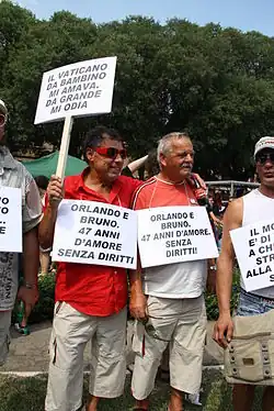 Photographie de deux hommes plutôt âgés, côte à côte, avec des pancartes portant à slogans.