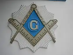 Symbole maçonnique : G (Dieu) équerre et compas.