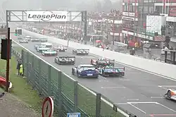 Photographie d'un départ de course automobile, vue de derrière