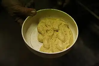 photo couleur d'un plat contenant une pâte jaune pâle granuleuse de consistance épaisse.