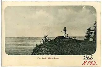 Photo en noir et blanc montrant le phare surplombant le cap en 1906. On distingue un trois-mâts sur l'horizon.