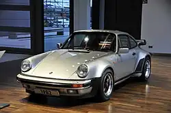 Une Porsche 911 Turbo grise similaire à celle présente dans le jeu, exposée à l'Autostadt Wolfsburg.
