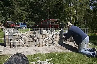 L'artiste Jocelyn Maltais plaçant quelques roches dans le Tacon Site des Caps.