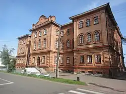Photographie en contre-plongée d'un bâtiment marron de style néo-russe avec deux étages en plus du rez-de-chaussée.