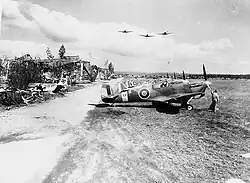 Avions de la FAFL alignés devant les hangars détruit et une épave d'avion de la Luftwaffe.