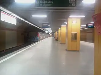 Le quai central avec une rangée centrale de colonnes de soutènements et à gauche l'arrivée d'une rame