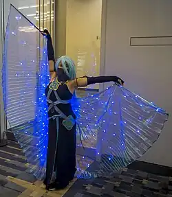 Personne déguisée dans une robe de couleur nuit et avec une perruque bleue.