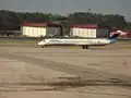 Un Delta Air Lines MD-88 circule devant les deux hangars de la 117e escadre de ravitaillement en vol de la Garde nationale aérienne des États-Unis, un KC-135 de la 117e escadre, et la caserne des pompiers de l'aéroport de Birmingham–Shuttlesworth.