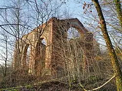 Un bâtiment trapue derrière des arbres.