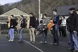 Groupe de musiciens debout, avec un tambour et des instruments à corde.