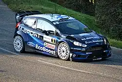 Voiture bleu électrique, vue de trois-quarts sur de l'asphalte.
