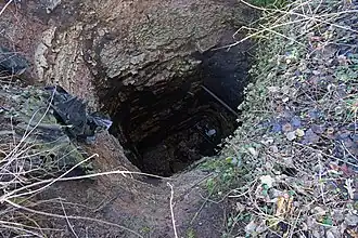 Photo couleur d'un trou rectangulaire dans le sol, profond d'une dizaine de mètres.