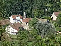 Groupement de maisons autour d'un bâtiment surmonté d'un clocheton en pointe.
