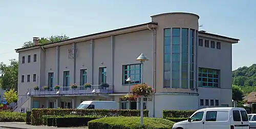 Vue d'un bâtiment parallélépipédique avec une tour partiellement vitrée dans un angle.