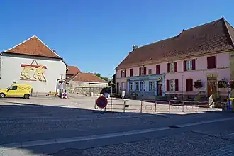 Un bâtiment ancien à grand toit, au fond d'une petite place.