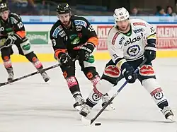 Markus Schlacher, avec la rondelle, poursuivi par Kyle Beach lors d'un match de l'EBEL.