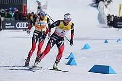 Deux fondeuses, de face, l'une derrière l'autre, dans un virage.