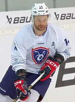 Photographie d'un joueur de hockey sur glace avec un maillot blanc frappé d'un général romain.