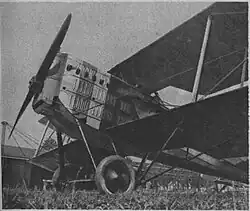 Photographie noir et blanc de l'avion d'un biplan, zoom sur le moteur et son échappement.