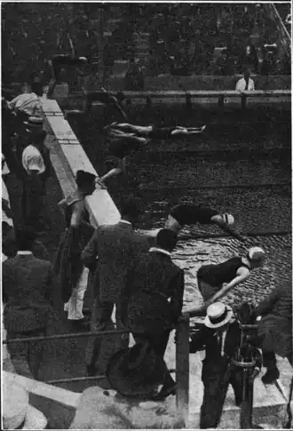 photo noir et blanc : départ d'une épreuve de natation : des nageuses plongent, entourées d'une foule