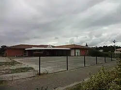 Bâtiment moderne rouge avec auvent et cour en goudron.