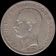 Photographie d'une pièce de monnaie argentée montrant le profil d'un homme moustachu.