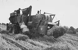 Moisson à la moissonneuse-batteuse avec récolte du grain en sacs et de la paille en bottes, vers 1960, Pays-Bas