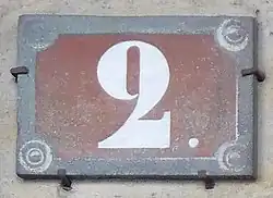 Numéro peint en blanc sur fond rouge, conformément à la réglementation de 1805 pour les rues parallèles à la Seine.